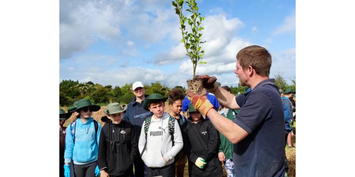 Antony Shadbolt showing students how to plant trees